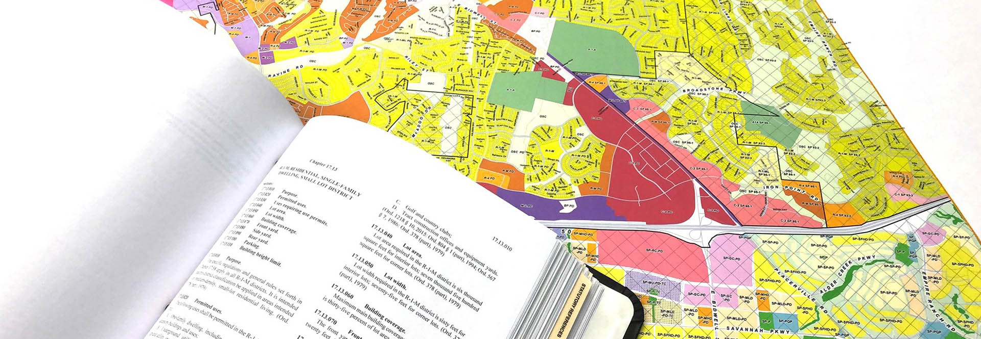 zoning update banner photo of multicolored zoning map and code book on top of the map