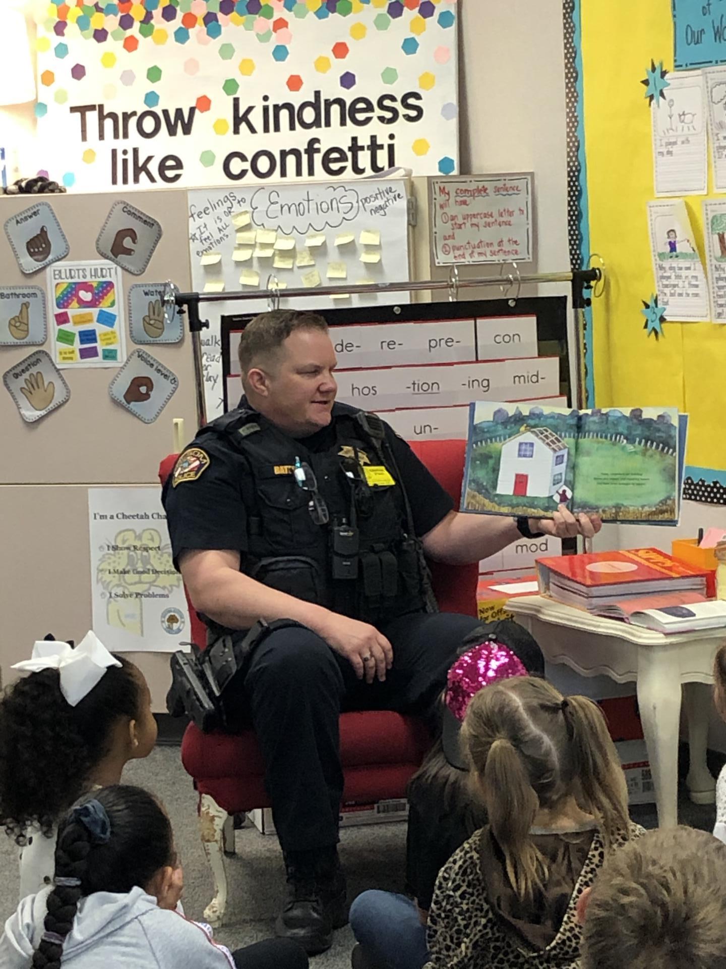 Officer reads a book to class of children