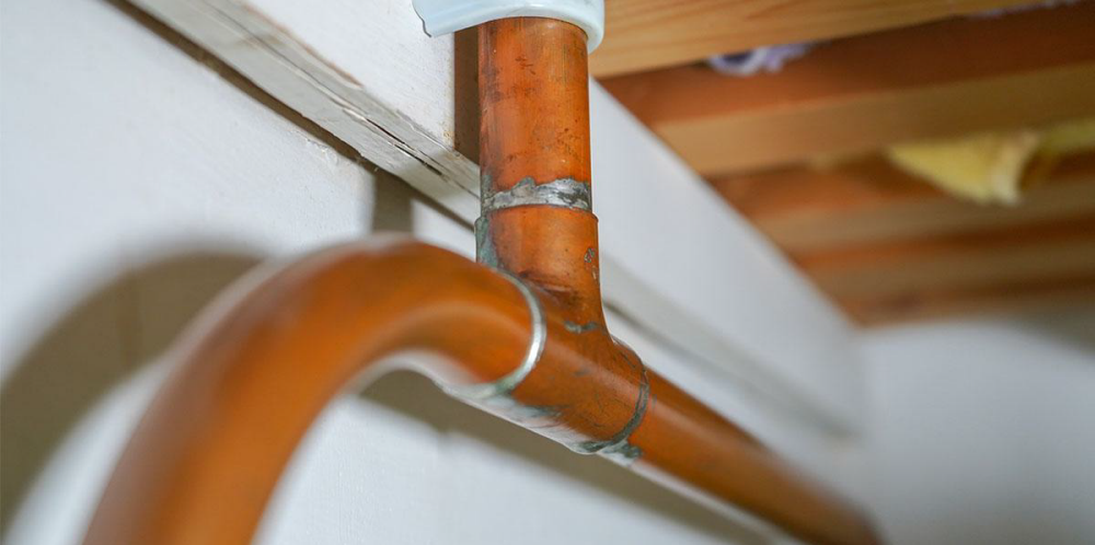 copper pipe picture attached to white wood with a wooden plan ceiling in the background