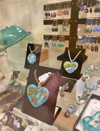 gifts retail jewelry on display in a glass box, filled with colorful handmade necklaces and earrings