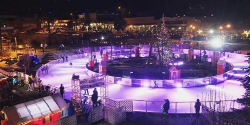 ice rink during winter with purple lights and people skating on the circular ice rink with a christmas tree in the middle