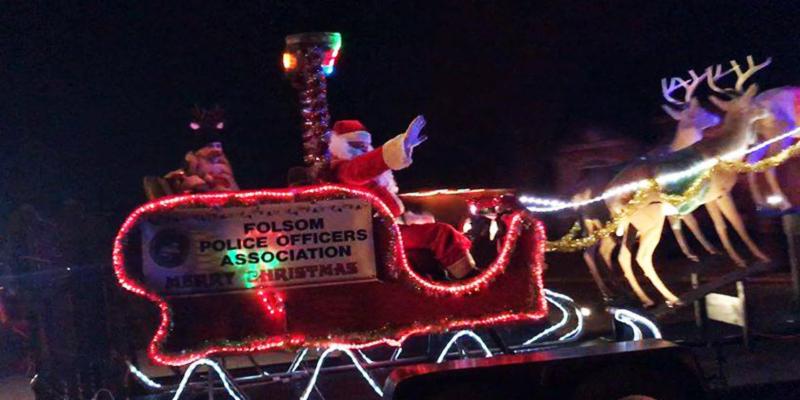 Santa on his sleigh going through neighborhoods and waving to residents on a lit sleigh with reindeer and a sign for Folsom Police Officers Association Merry Christmas
