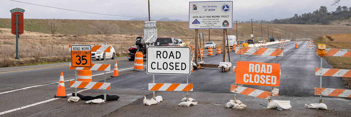 Public Works Banner of Green Valley Rd. widening project with Road Closed and construction signs.