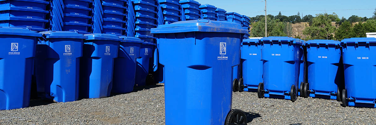 recycling bins lined and stacked up in the background with a single recycling bin in the center of the photo.