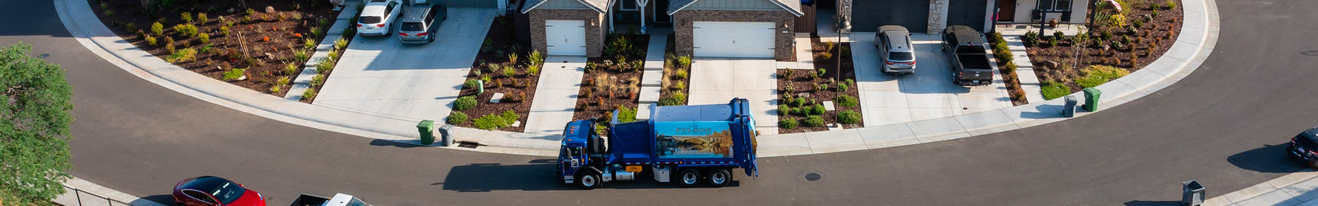 Solid Waste Banner of blue waste truck going to pick up cans in a neighborhood