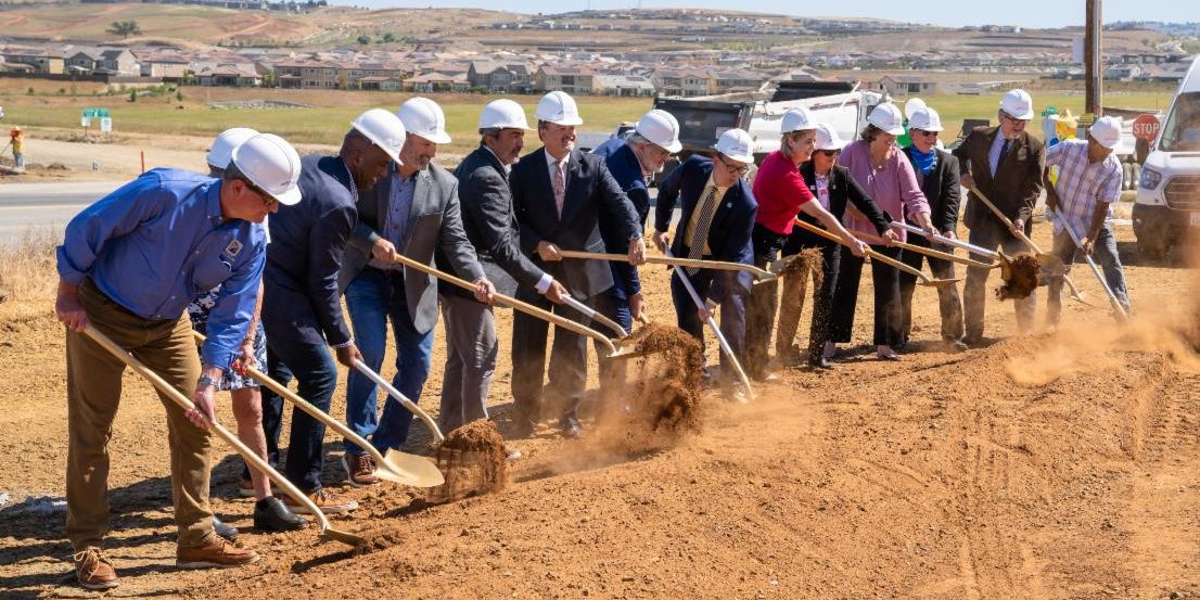 Cap SE Connector Groundbreaking May 2021. City employees, Mayor, stakeholders in a row shoveling dirt and wearing hardhats