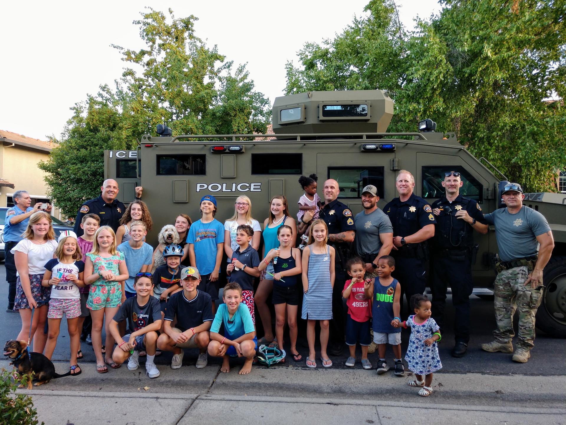 A neighborhood group from National Night Out 2019 with Police Officers in front of SWAT Vehicle