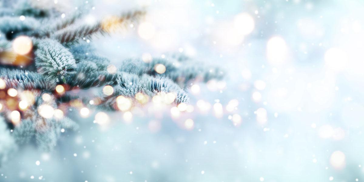 holiday image of a christmas tree with glittering lights and snow falling