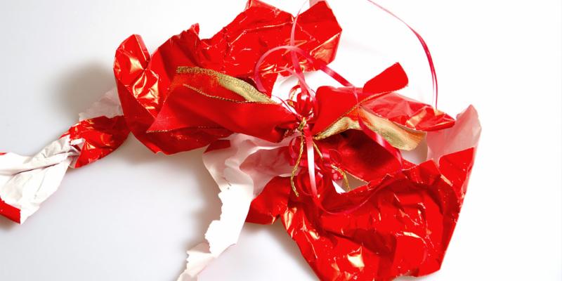 red gift wrapping paper that has been ripped and opened with red and gold string and ribbon