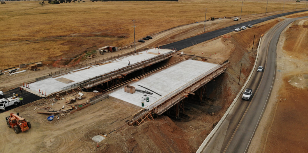 CONSTRUCTION - Sacramento Capital SouthEast Connector Expressway with yellow hills and trees in the background of the drone shot of major construction of two overpasses 